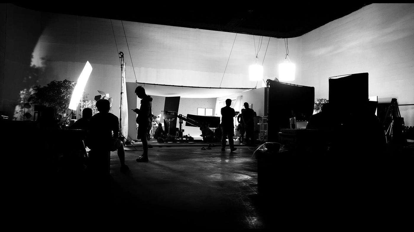 Film crew silhouetted on a studio set under suspended lights