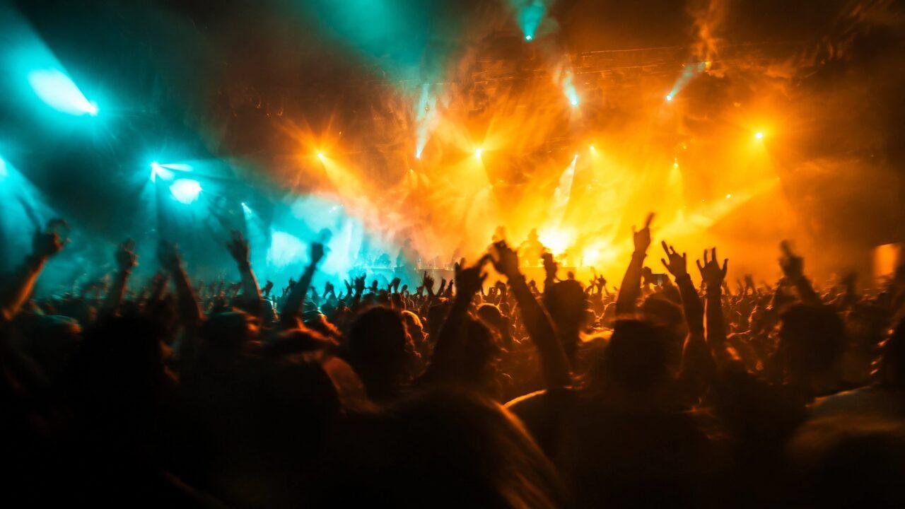 Crowd at a live show with amber and teal stage lights